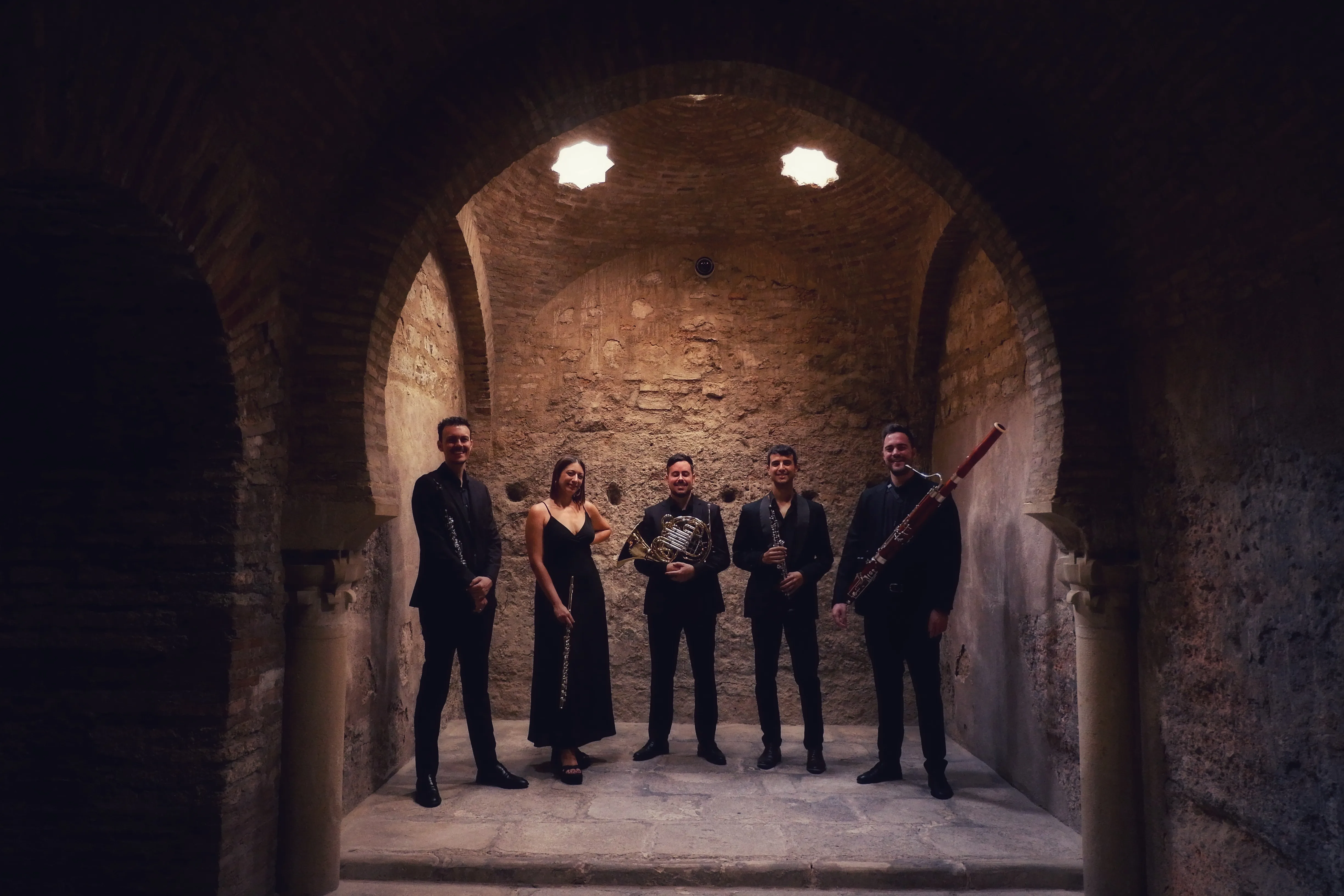Zayt Ensemble posando con sus instrumentos bajo la bóveda de piedra de un baño árabe